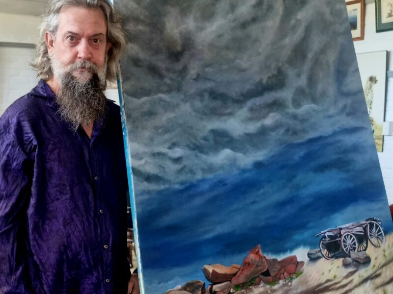 Resident artist John Blackwell standing beside his painting 'Yacka Storm'